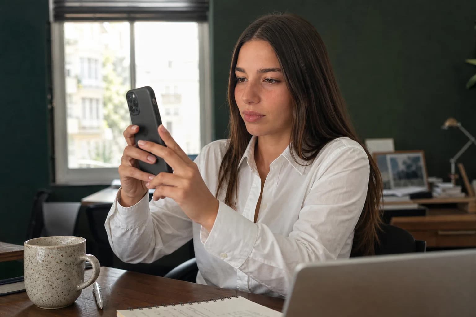 Woman filming a desk scene with her phone, focused on the subject rather than the camera