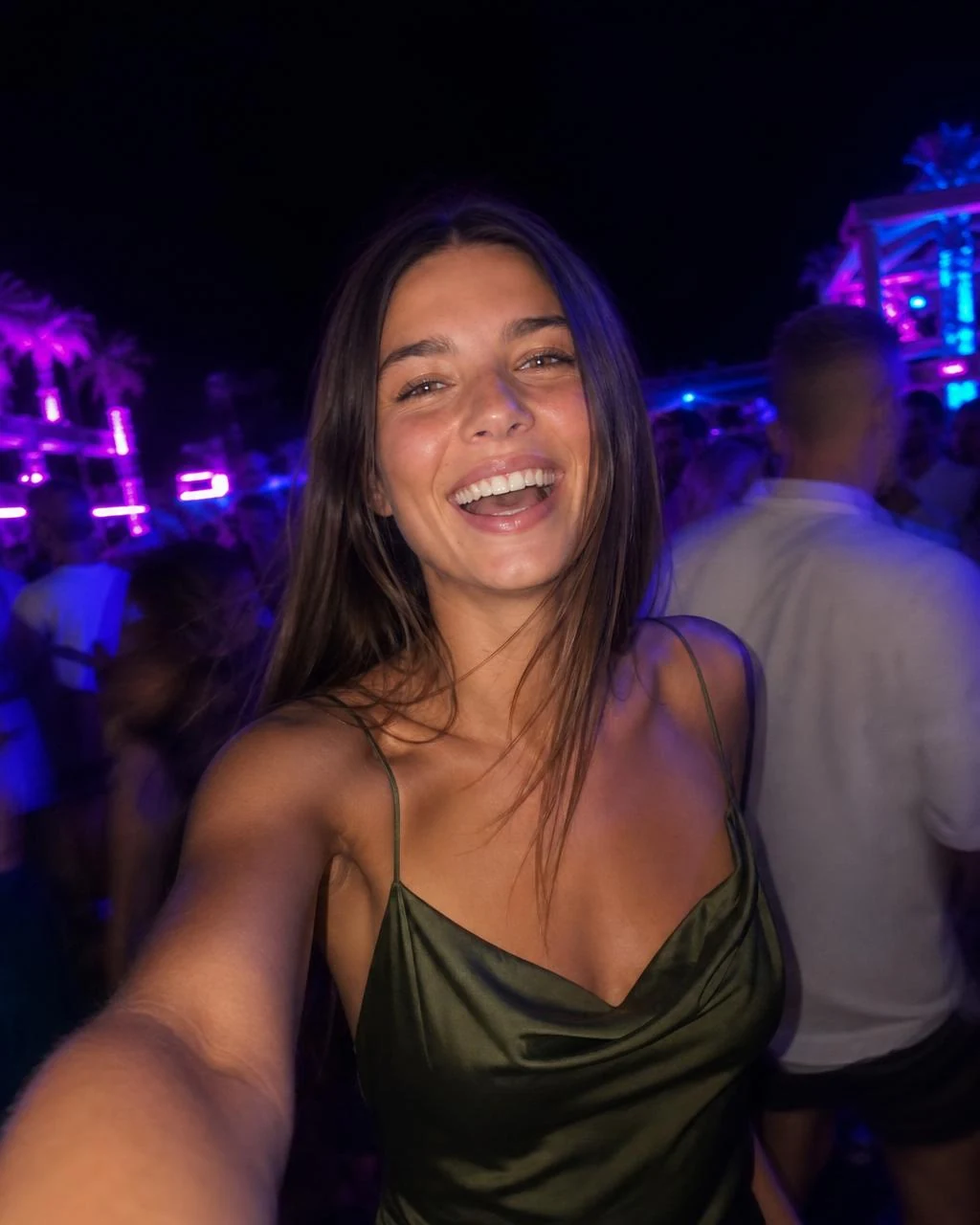 Identity lock anchor: AI-generated influencer persona, brunette in an olive silk slip top, smiling selfie at an outdoor night event with neon lights