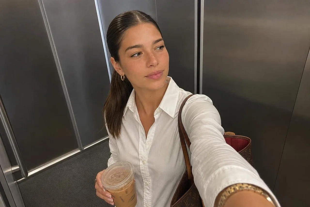 Same AI influencer in an elevator mirror selfie, crisp white button-down with iced coffee and a tote bag