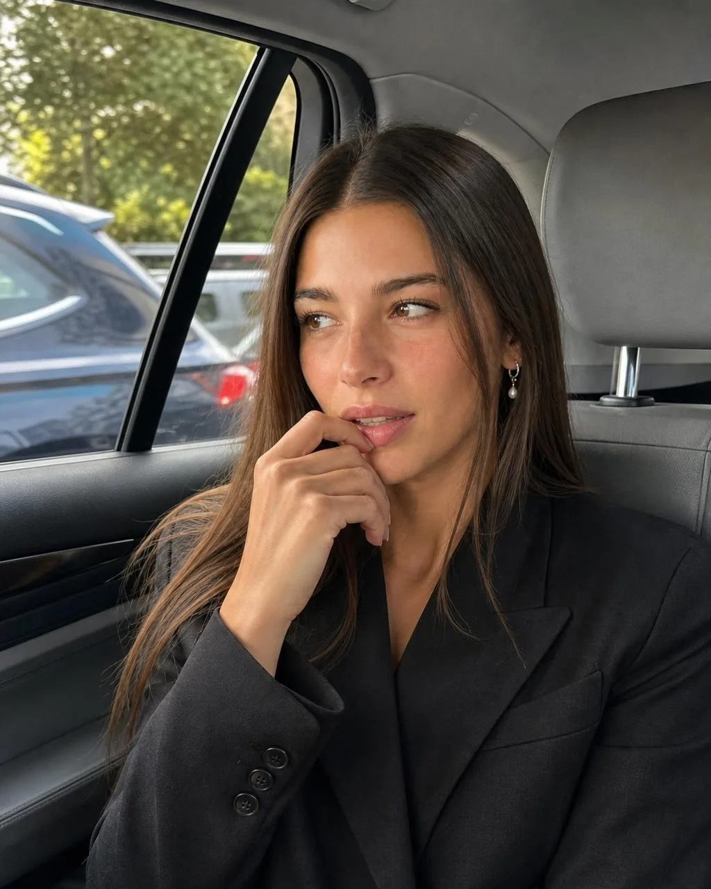 Cladegrove generated photo of the saved character in the back seat of a car looking out the window, black tailored blazer, soft daylight, produced from one short prompt and one credit